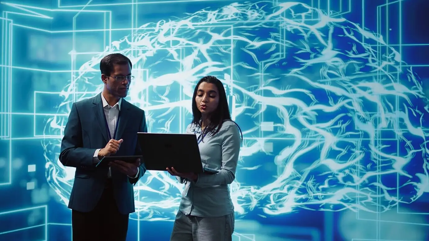 Mitarbeitende lösen Aufgaben auf Laptop und Tablet, auf denen KI-Software läuft.